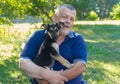 Positive portrait of Ukrainian senior man sitting in summer garden  with sweet puppy on the hands Royalty Free Stock Photo