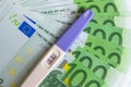 A positive pregnancy test on the euro banknotes background