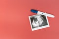 A positive pregnancy test and ultrasound photo on a pink background. A positive pregnancy test result.