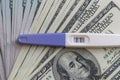 A positive pregnancy test on the US dollars background