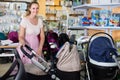 positive pregnant woman looking for baby carriage at kids shop