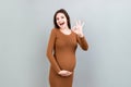 positive pregnant woman showing okay gesture against her belly at colored background. Easy and happy pregnancy. Copy Royalty Free Stock Photo