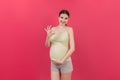 positive pregnant woman showing okay gesture against her belly at colored background. Easy and happy pregnancy. Copy Royalty Free Stock Photo