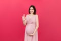 positive pregnant woman showing okay gesture against her belly at colored background. Easy and happy pregnancy. Copy Royalty Free Stock Photo