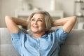 Positive pretty elderly mature woman relaxing on home couch Royalty Free Stock Photo