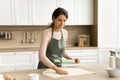 Positive pretty young Latin woman in apron baking in kitchen