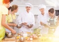 Positive professional chefs in white uniform conducting culinary masterclass for tweens Royalty Free Stock Photo