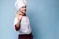 Positive professional happy man chef showing tasty ok sign isolated on light blue.