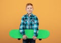 Positive red-haired boy with skateboard deck on yellow Royalty Free Stock Photo