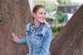 Positive redhead Caucasian woman posing at tree in park at autumn looking away Royalty Free Stock Photo