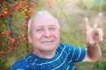 Positive retired grandfather, makes selfie photo with a smartphone in the park. an elderly man walks in nature