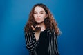 Positive romantic curly girl sending air kiss. standing over blue background. Love or romance concept
