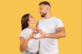 Positive romantic millennial european family in white t-shirts hugs, making heart gesture with hands