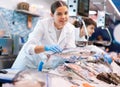 Positive saleswoman demonstrating bonito fish in fish store