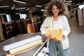 positive saleswoman holding pastel yellow fabric