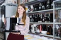 Positive saleswoman suggesting coffee brewer in shop