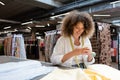 positive saleswoman using smartphone near fabric