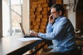 Positive senior bearded man with grey hair drinking coffee and using laptop at cafe, copy space. Stylish aged Royalty Free Stock Photo