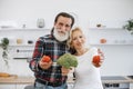 Positive senior couple man and blonde woman having fun with vegetables. Royalty Free Stock Photo