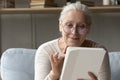 Positive senior digital tablet user woman in glasses reading ebook Royalty Free Stock Photo