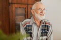 Positive grandfather with grey hair and beard sitting at home Royalty Free Stock Photo