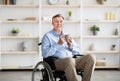 Positive senior impaired man in wheelchair drinking coffee or tea at home Royalty Free Stock Photo
