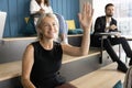 Positive senior learning employee woman raising hand on lecture