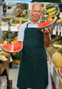 Owner of greengrocery offering fruits and vegetables Royalty Free Stock Photo