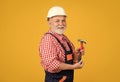 positive senior man carpenter in hard hat on yellow background Royalty Free Stock Photo