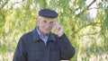 Positive senior man wearing cap looking from under glasses with staring look.