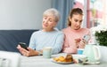 Senior woman and adult daughter sitting at table with cell phones Royalty Free Stock Photo