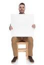 Positive smart casual man holding blank billboard and smiling