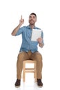 Positive smart casual man holding tablet and pointing up