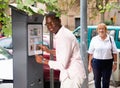 Positive African American man buying ticket for street parking in modern parking meter Royalty Free Stock Photo