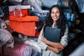 Positive smiling employee with notepad is in the storage full of cloth