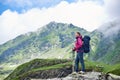 Positive smiling female tourist admiring magnificent nature with foggy green rocky mountains in Romania