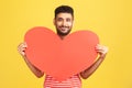 Positive smiling man in love holding in hands big red paper heart looking at camera with smile, confessing his love, romantic