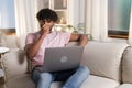 A positive smiling mestizo guy sits in the room on the sofa and enjoys relax after work or study in the cozy home Royalty Free Stock Photo