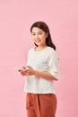 Positive smiling woman holds modern cellular, enjoys wireless internet over pink background