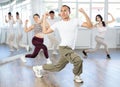 Positive smiling young man dancing hip hop with group of guys and girls in dance class Royalty Free Stock Photo