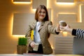 Positive smiling young woman in a jacket shares takeaway coffee with co-workers in the office Royalty Free Stock Photo