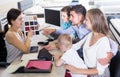 saleswoman in furniture store helping young family in choice of mattress material