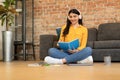 Positive spanish teen lady taking notes in notepad, writing in diary and listening music in headphones