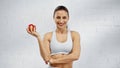 Positive sportswoman holding apple and looking