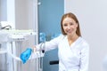 Positive stomatologist sitting near dental equipment in modern hospital room