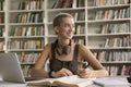 Positive student girl doing academic research study in university library Royalty Free Stock Photo