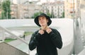 Positive stylish young man in street clothes and panama posing for the camera on the background of the velodrome, looking at the