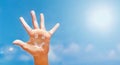 Positive symbol drawing by sunscreen sun cream, suntan lotion on caucasian open hand on blue sky background. Royalty Free Stock Photo