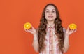positive teen girl hold citric fruit on orange background