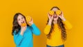 positive teen girls hold orange fruit on yellow background